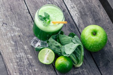 Kırsal ahşap masada cam ve lahana yapraklı yeşil elma püresi. Yaz Detox sallama arkaplanı