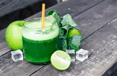 Kırsal ahşap masada cam ve lahana yapraklı yeşil elma püresi. Yaz Detox sallama arkaplanı