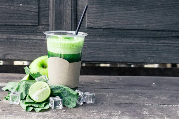 Green apple smoothie in glass and kale leaves on rustic wooden table. Summer Detox shake background