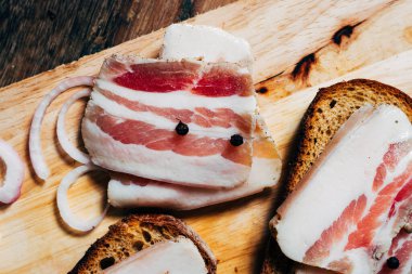 Ahşap masadaki masa örtüsünün üzerinde domuz yağlı ve siyah ekmekli sandviç.