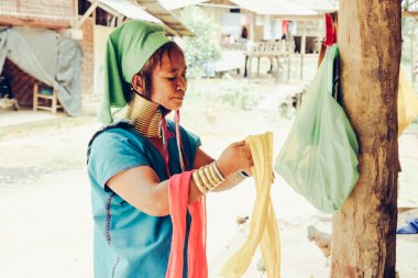 Uzun Boylu Kadın Tayland 'ın kuzeyindeki kabile köyünde evinin önünde kumaş dokuyordu..