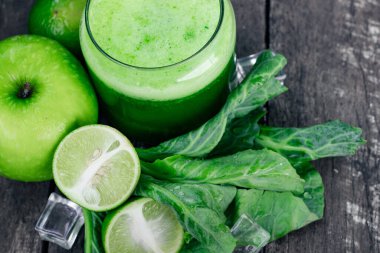 Kırsal ahşap masada cam ve lahana yapraklı yeşil elma püresi. Yaz Detox sallama arkaplanı