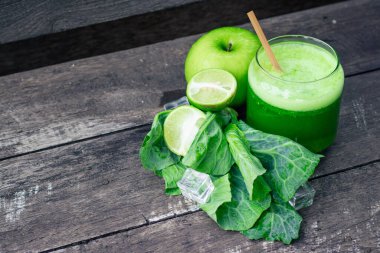 Kırsal ahşap masada cam ve lahana yapraklı yeşil elma püresi. Yaz Detox sallama arkaplanı