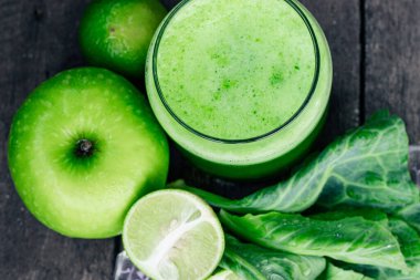 Kırsal ahşap masada cam ve lahana yapraklı yeşil elma püresi. Yaz Detox sallama arkaplanı