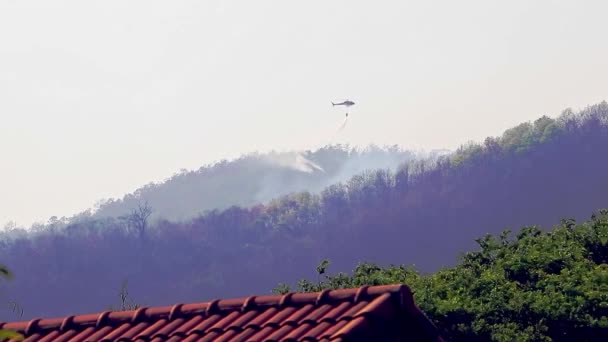 Brandbekämpfung aus der Luft mit Flächenbränden während der Dürre in den Bergen. Hubschrauber löschten Waldbrand. Entwaldung und Klimakrise. — Stockvideo