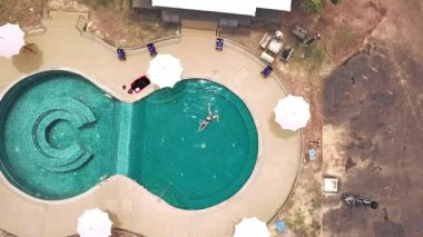 Açık yeşil yüzme havuzunda yüzen genç bir kadın. Açık hava aktiviteleri. Sağlıklı bir yaşam tarzı. Üst görüntü video 4k.