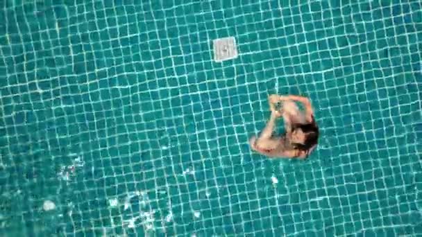若い女性がオープングリーンスイミングプールで泳いでいます。野外活動。健康的なライフスタイル。トップ表示航空ビデオ4k. — ストック動画