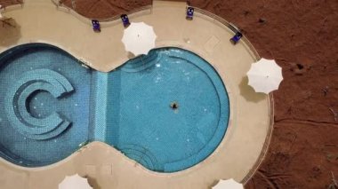 Açık mavi yüzme havuzunda yüzen genç bir kadın. Açık hava aktiviteleri. Sağlıklı bir yaşam tarzı. Üst görüntü video 4k.