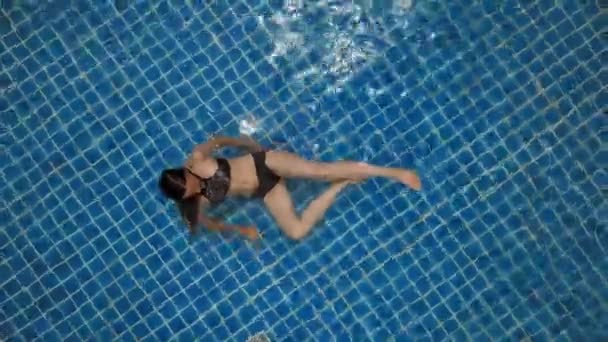 Junge Frau schwimmt im offenen blauen Schwimmbad. Aktivitäten im Freien. Gesunder Lebensstil. Luftbild von oben 4k. — Stockvideo