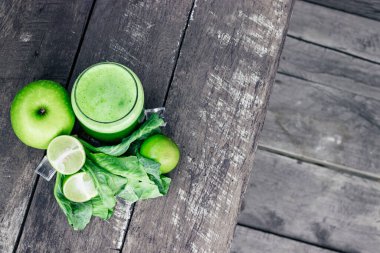 Kırsal ahşap masada cam ve lahana yapraklı yeşil elma püresi. Yaz Detox sallama arkaplanı