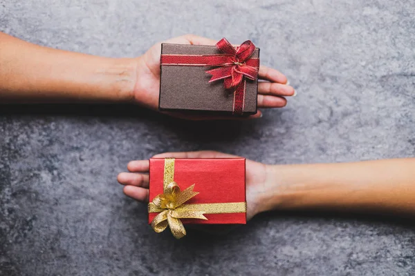 Kadın el kahverengi hediye kutusu tutarak ve birbirlerine bir gri taş tabloda verilen bir kırmızı hediye kutusu