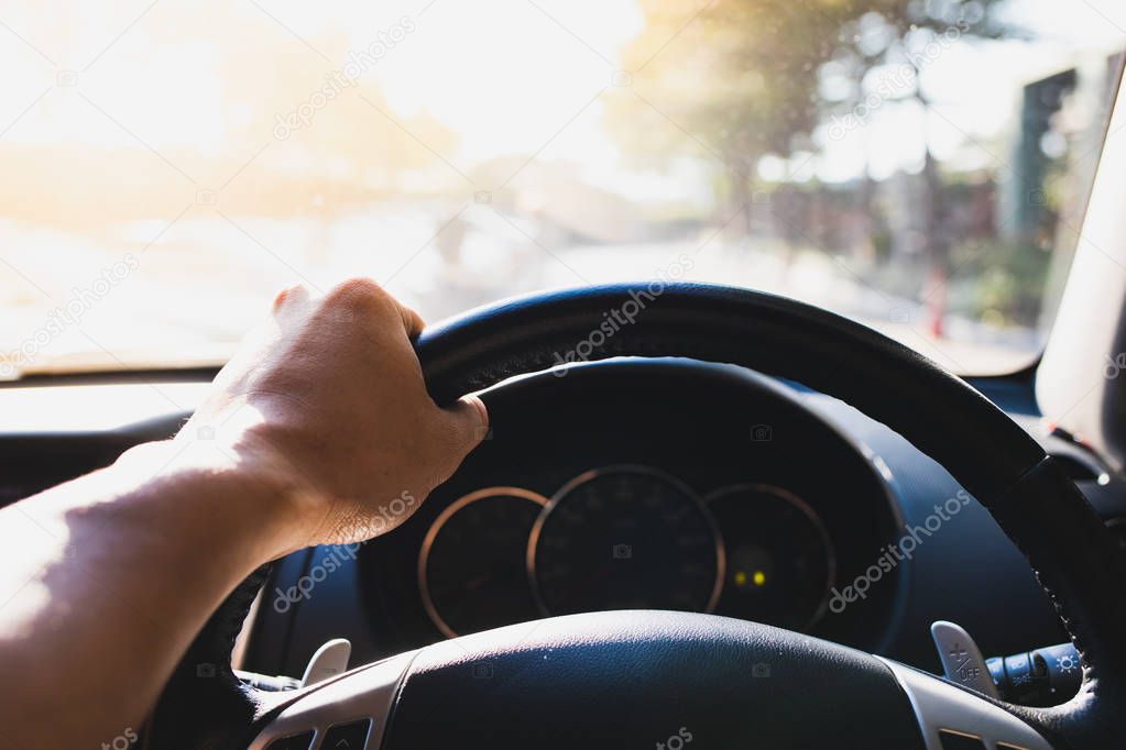 The left hand of the man holding the steering wheel