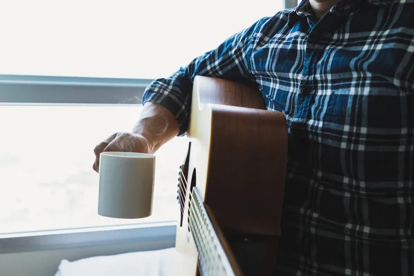 コーヒーのマグカップとギターを保持している男性 — ストック写真