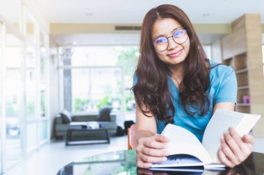 Asyalı kadınlar gülümsüyor ve kitap okuyor.