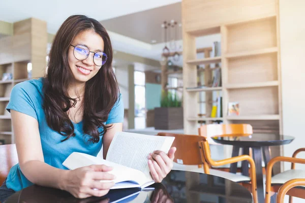Asyalı kadınlar gülümsüyor ve kitap okuyor.