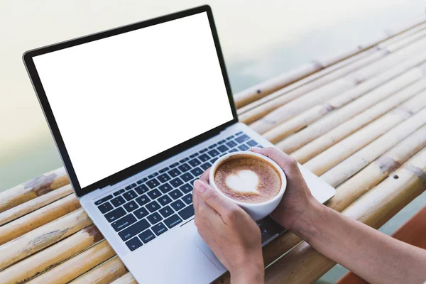 Kadınlar elinde sıcak bir espresso bardağı tutarken dizüstü bilgisayarın modelini giyerler.