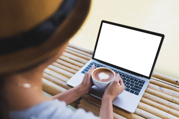 Kadınlar elinde sıcak bir espresso bardağı tutarken dizüstü bilgisayarın modelini giyerler.