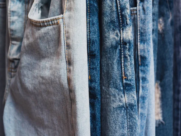 Close up row of many blue jeans are hanging — Stock Photo, Image