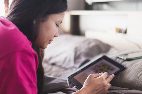 Mutlu Asyalı kadınlar yatak odasından online alışveriş yapmak için tablet kullanıyorum. Korona virüsü salgını sırasında karantina