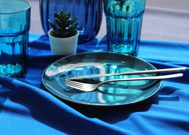 Yemek odası iç dekorasyon, masa düzenleme. Masanın üzerinde mavi bir masa örtüsü ve mavi tabaklar var..