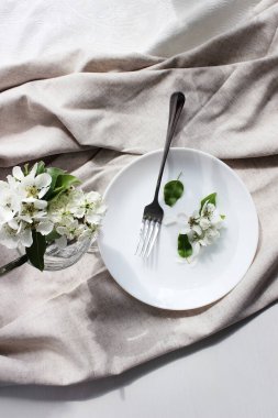Masada keten katlı beyaz tabak var. Tabakta bahar armudu çiçekleri. Masa dekoru, iç dekorasyon. yakın plan.