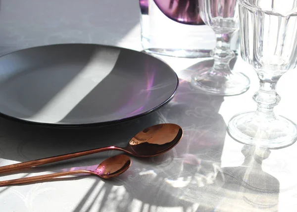 table setting close-up plate and cutlery. gray plate with copper cutlery.