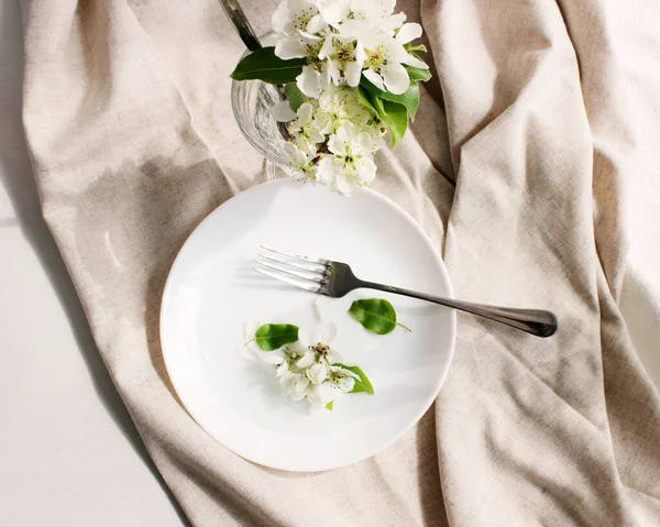 Masa düzenleme detayları. Armut çiçekleri güneşte beyaz bir tabakta. iç ayrıntılar.
