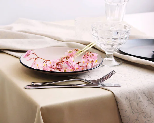 Μπεζ Πιάτα Και Μαχαιροπίρουνα Ένα Τραπέζι Διακόσμηση Από Ροζ Λουλούδια — Φωτογραφία Αρχείου
