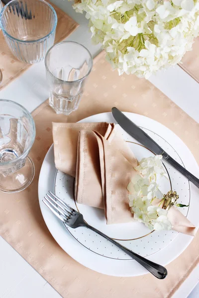 Masa dekorasyonunun ayrıntıları. Sofra takımı, çatal bıçak takımı ve çanak çömlek. Masada ve tabakta portakal peçeteleri var..