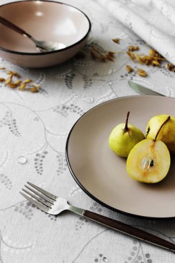 Masa takımı. Tabaklar masada, armut ve çatal bıçak takımı var..