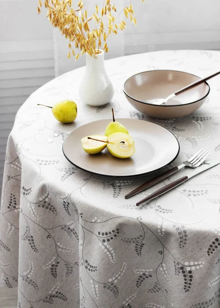 Yuvarlak bir masada armutlu Cutlery.plakalı masa ayarları, üst görünüm.