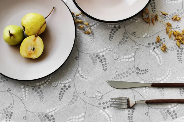 Masa takımı. Tabaklar masada, armut ve çatal bıçak takımı var..