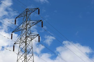 Yüksek gerilim elektrik pilon veya güç iletim kulesi kabloları ile. Arka plan beyaz bulutlar ile mavi gökyüzü. İyi kopya alanı.