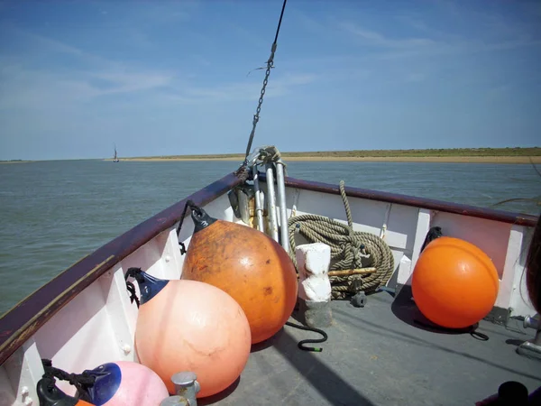 船弓与橙色和粉红色的挡泥板和绳子盘绕准备使用 河和瓦片海滩的背景以蓝天 — 图库照片