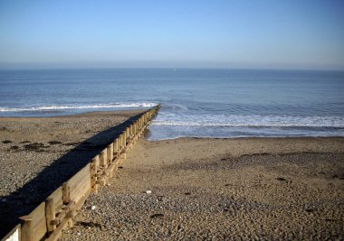Shingle ve sakin deniz ve dalgakıran (groyne) east Coast of Yorkshire, İngiltere ile kum plaj. Arka plan mavi gökyüzü ve denizin. Güneş ışığından sağ tarafı.