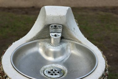 Metal park çeşme ile bir çakıl taşı kesikli dış beton bir kaide üzerinde kase ile.