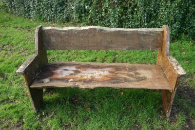 Rustik koltuk kaba kesilmiş ağaç plakalar yaptı. Koltuk giyilir. Arka plan otu ve çit.