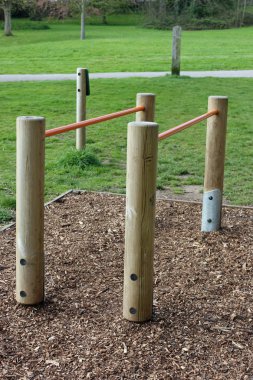 Paralel bar fitness ekipmanları ile temel bir ahşap çip kabuk bir parkta üzerindeki ahşap metal ve çim ve ağaç arka planda çim.