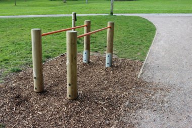 Paralel bar fitness ekipmanları ile temel bir ahşap çip kabuk bir parkta üzerindeki ahşap metal ve çim ve ağaç arka planda çim.