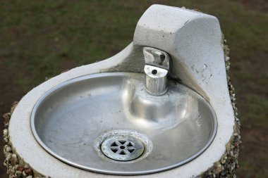 Metal park çeşme ile bir çakıl taşı kesikli dış beton bir kaide üzerinde kase ile.