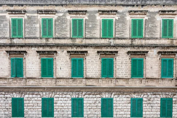 Green french shutters in a facade of a building
