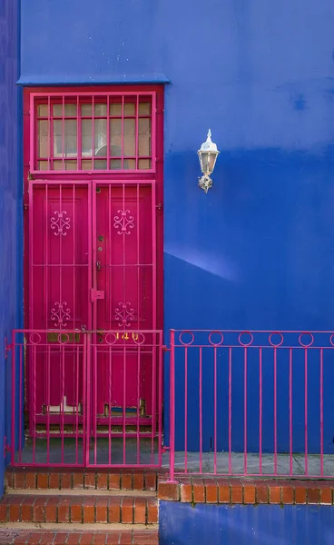 Cheerful colored facade of a private house in the Islamic district of Cape Town. In the entire neighborhood, houses look like this, all different and painted in bright colors. Even the doors and frames are painted in color.