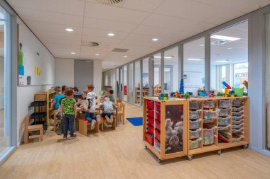 ARNHEM / NETHERLANDS - 28 Ağustos 2020: Anaokulundaki çocuklar oyuncaklarla oynuyorlar. Dolaplarda, kutularda ve kasalarda depolanan diğer oyuncaklar.