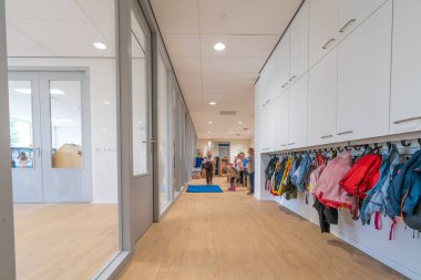 ARNHEM / NETHERLANDS - 28 Ağustos 2020: Bebek ve çocuklar için bir okul binasında paltolu ve sırt çantalı vestiyer