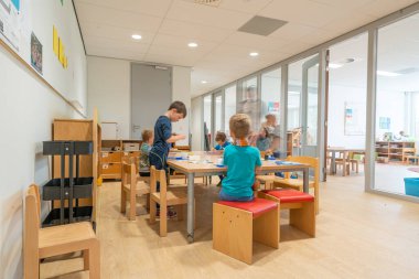 ARNHEM / NETHERLANDS - 28 Ağustos 2020: Anaokulundaki çocuklar oyuncaklarla oynuyorlar. Dolaplarda, kutularda ve kasalarda depolanan diğer oyuncaklar.