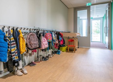 ARNHEM / NETHERLANDS - 28 Ağustos 2020: Bebek ve çocuklar için bir okul binasında paltolu ve sırt çantalı vestiyer