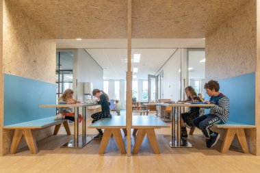 ARNHEM / NETHERLANDS - 28 AĞUSTOS 2020: İlkokuldaki çocuklar grup olarak çalışırlar. Modern bir okul binasındalar.