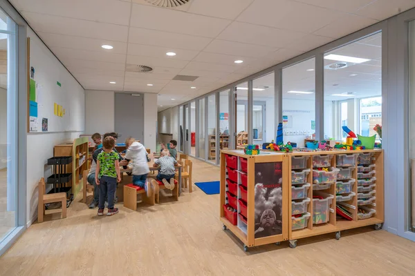 ARNHEM / NETHERLANDS - 28 Ağustos 2020: Anaokulundaki çocuklar oyuncaklarla oynuyorlar. Dolaplarda, kutularda ve kasalarda depolanan diğer oyuncaklar.