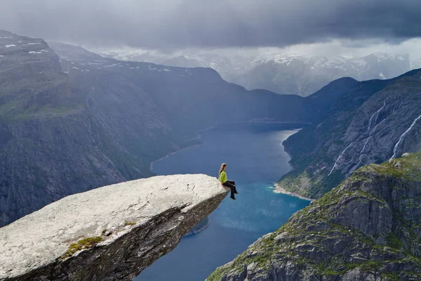 Trolltunga kaya (Troll dil rock) üzerinde oturan ve Norveç dağ manzarası arayan kız