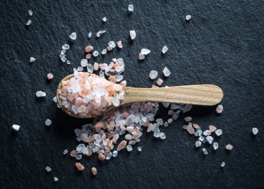 Pembe Himalaya tuz karanlık taş zemin üzerine tahta kaşıkla. üstten görünüm